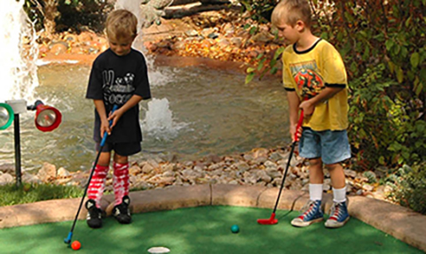 young boys playing mini golf